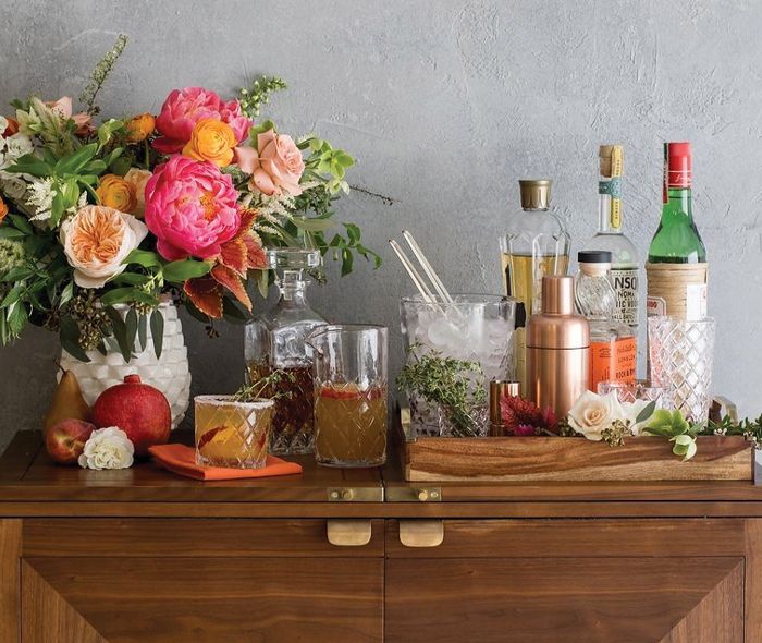 Close up of the drinks and flowers in a white vase over the Maxine Bar Cabinet. 