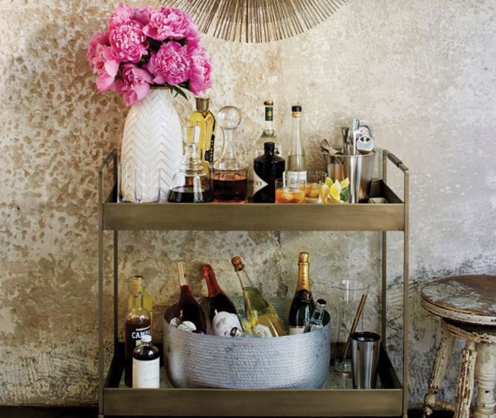 Bar cart with drinks and a white vase.