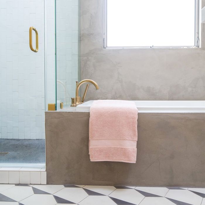 Bathtub pictured with a turkish cotton 800 gram towel hung over the ledge.