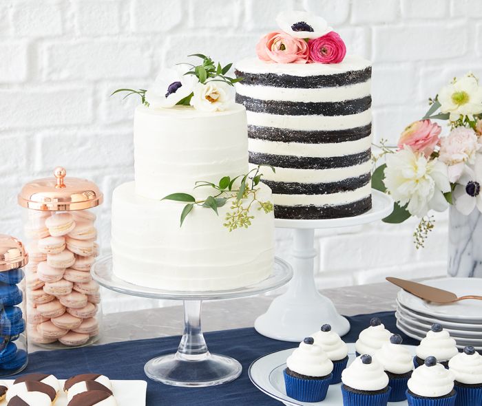 Two cakes on stands next to pastries.