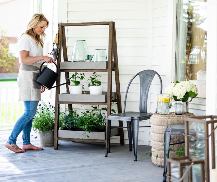 Woman watering plants on her front porch.