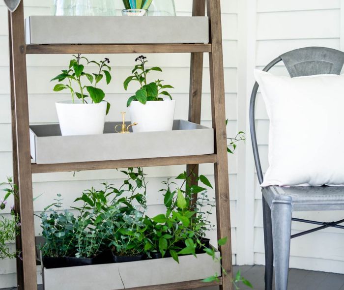 Plant stand next to a metal chair and a white pellow.