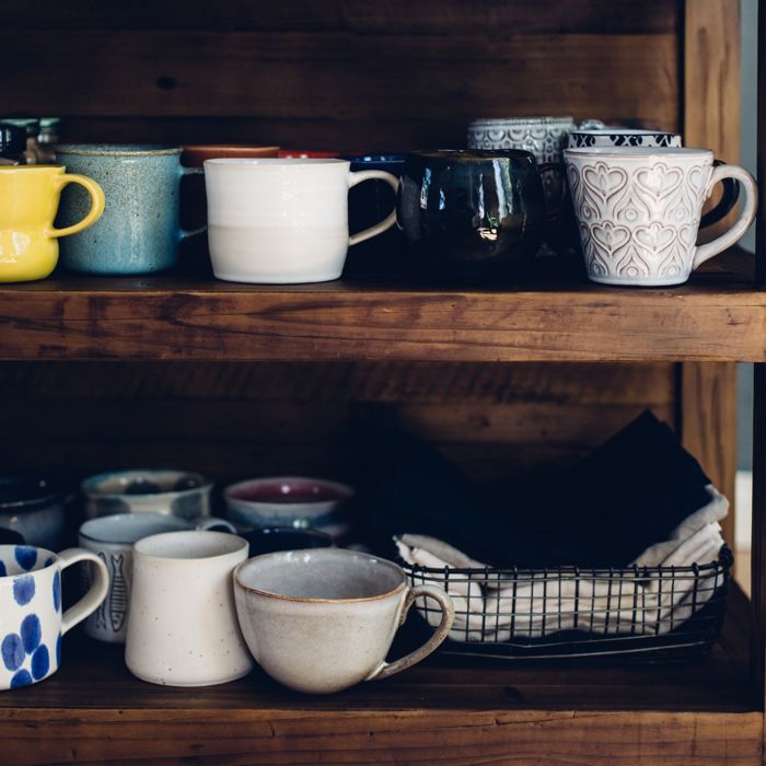 Different colored mugs on a wooden shelf