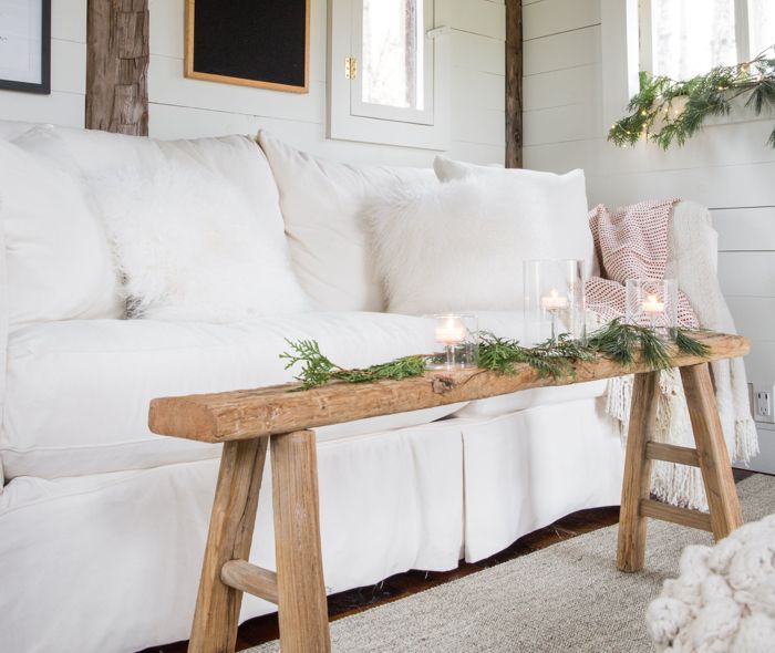 White couch with a small coffee table, decorated with a green garland and lit white candles. 