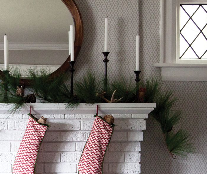 Cute animal ornaments peeking their heads out of stockings on a fireplace mantel