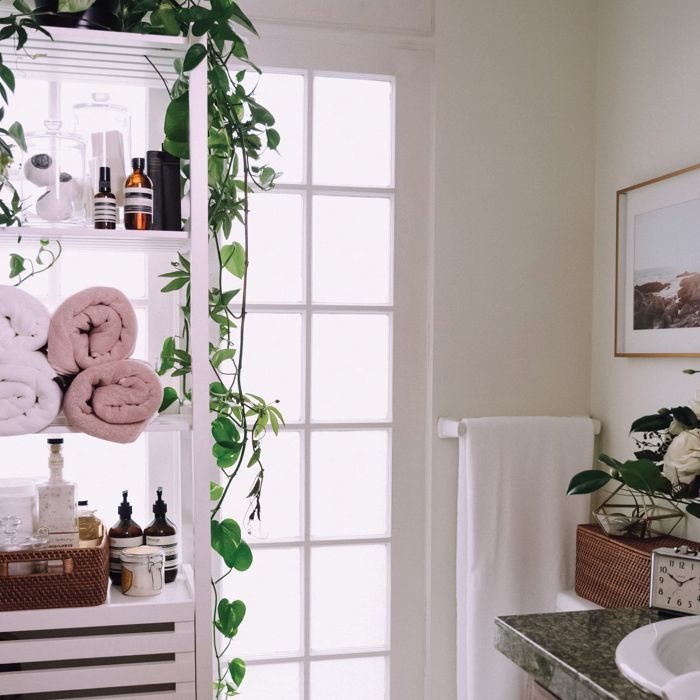 White bathroom with a white shelf that has pink and white towels.