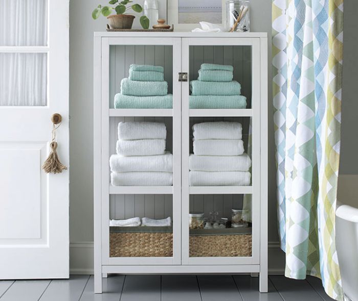 White storage cabinet with white and light blue towels.