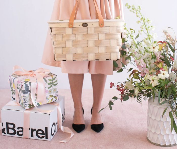  Woman holding a basket next to Crate&Barrel gift boxes.