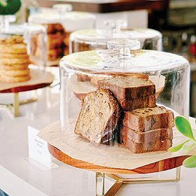 bread inside glass cake server on acacia wood pedestal