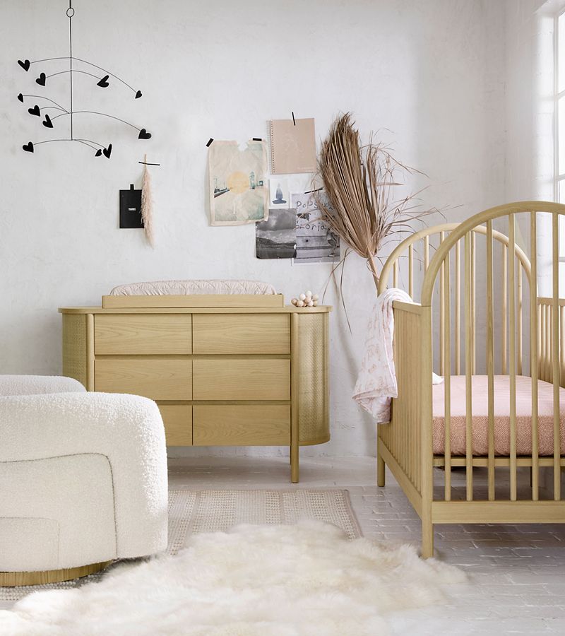 Pink and yellow children's bedroom; pink wood twin bed with throw pillows and stuffed pig, velvet pouf seat beside floral rug