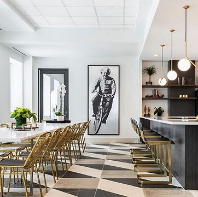 Modern art-deco inspired bar featuring black and brass details, a bold tiled floor and wall art of Einstein riding a bicycle 