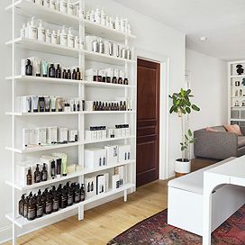 A large white shelf sits against a white wall, holding assorted bath products