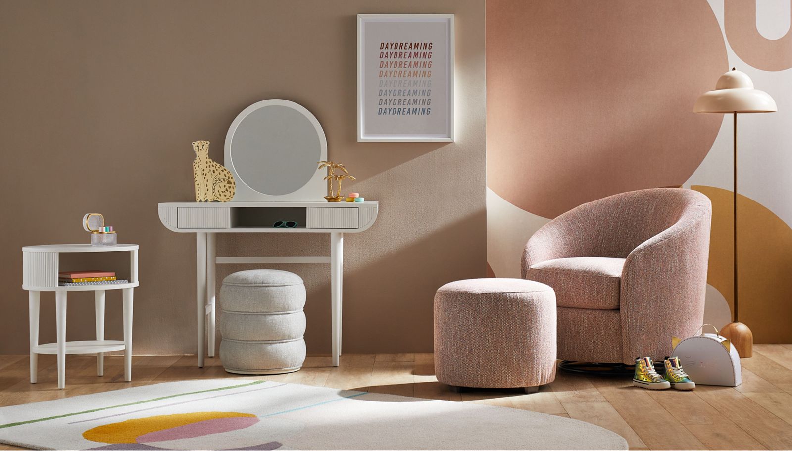 Blush-colored children's room with a light pink chair and round white mirror against the wall