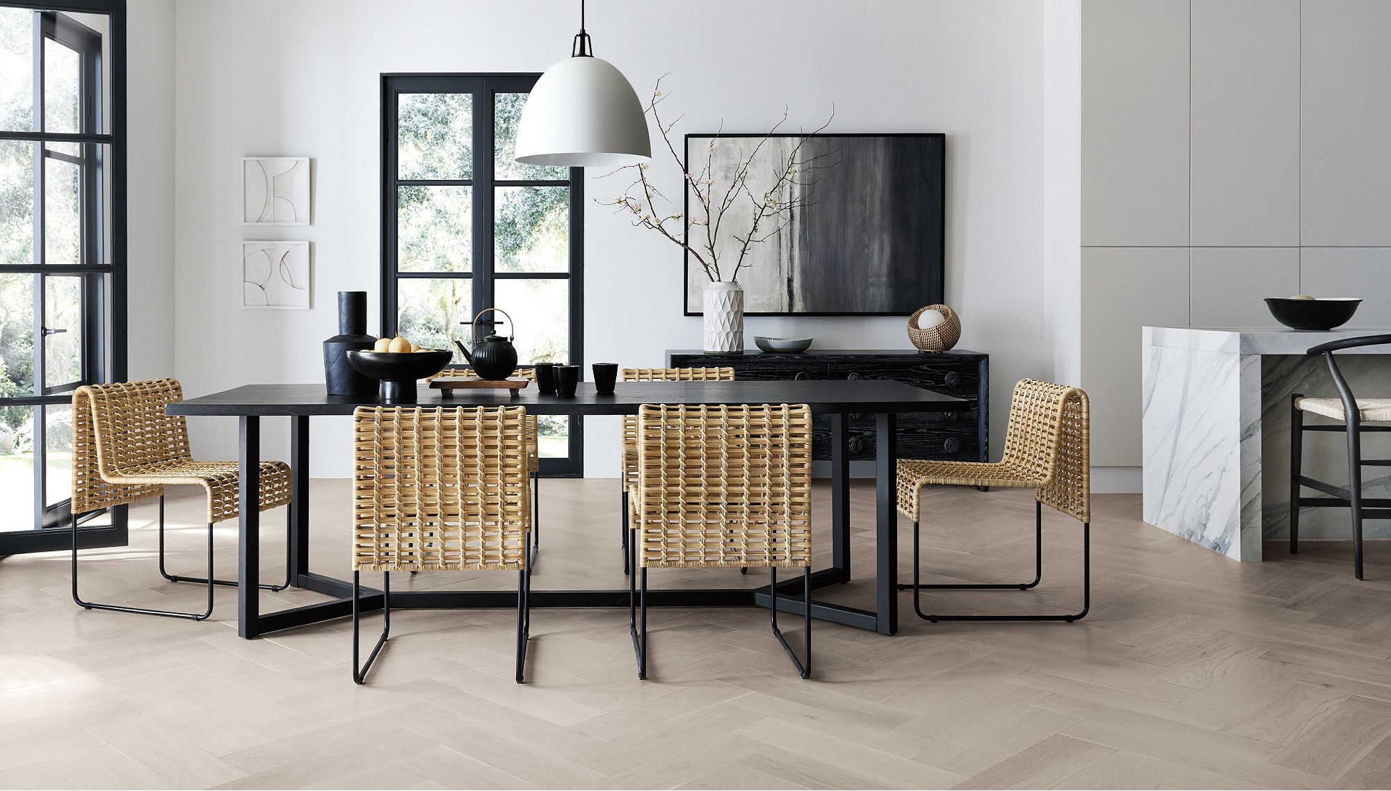 Spacious dining room with a black dining table, six brown chairs and a vase, fruit bowl and tea kettle on the table