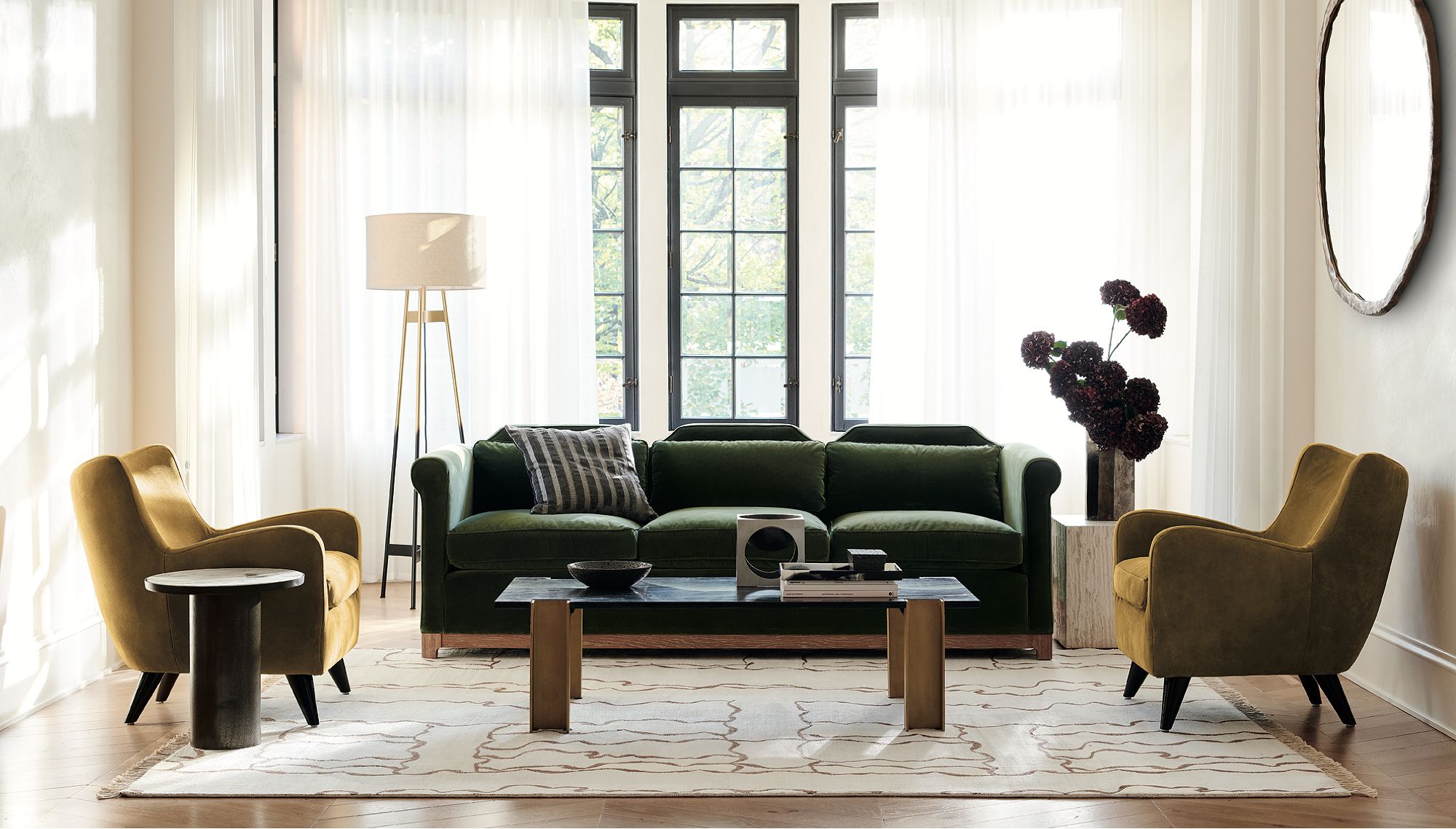 Living room with a dark green couch, two ochre accent chairs and a low coffee table in the center