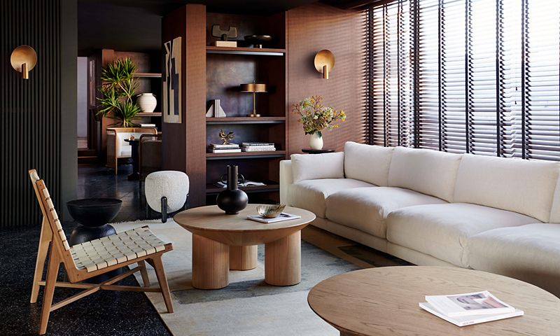 Room with long white couch and two circular wood accent tables