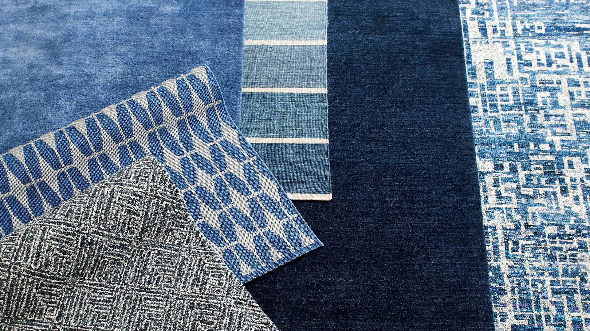 A variety blue patterned rugs layered on top of each other. Shop blue trend.