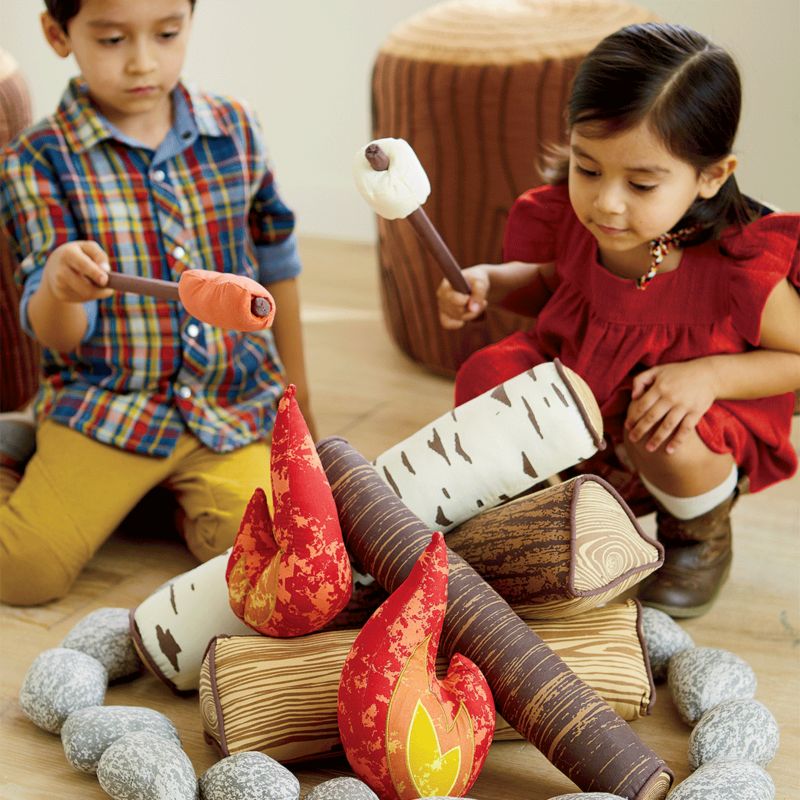 Girl and boy sitting by plush campfire set