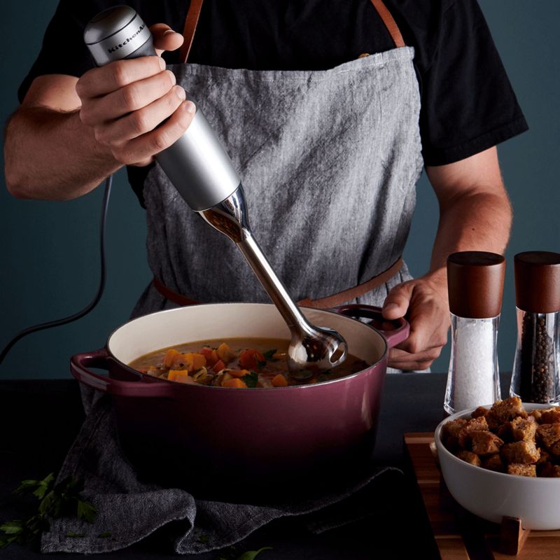 Man mixing soup blend with KitchenAid hand blender