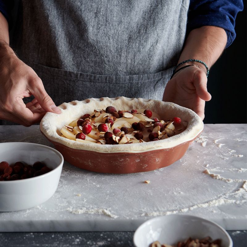 Hands molding crust of apply cherry pie in brown pie dish