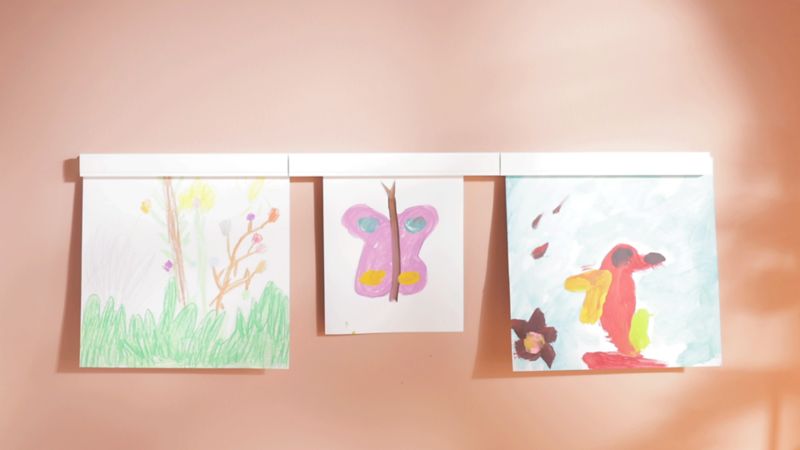 Artwork hanging from white art rail