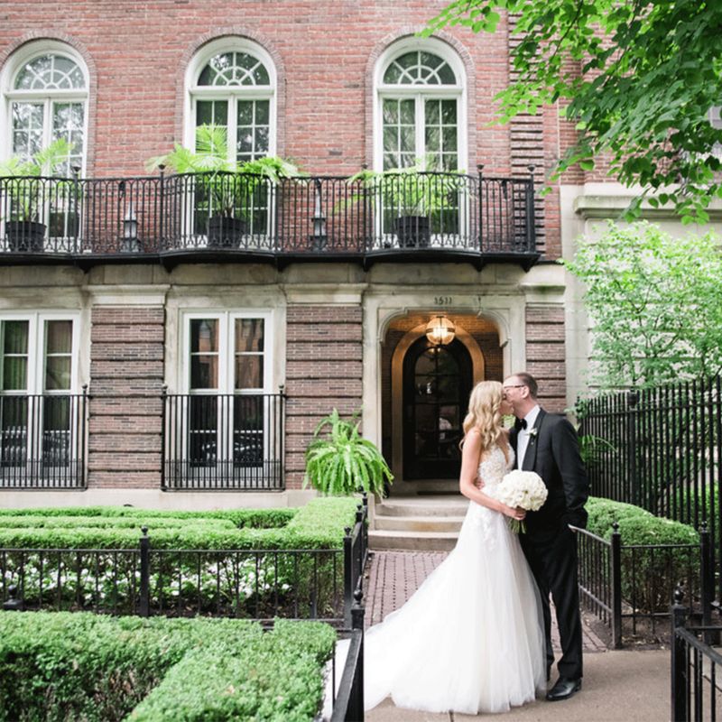 Couple on their wedding day standing outside of a brick townhome