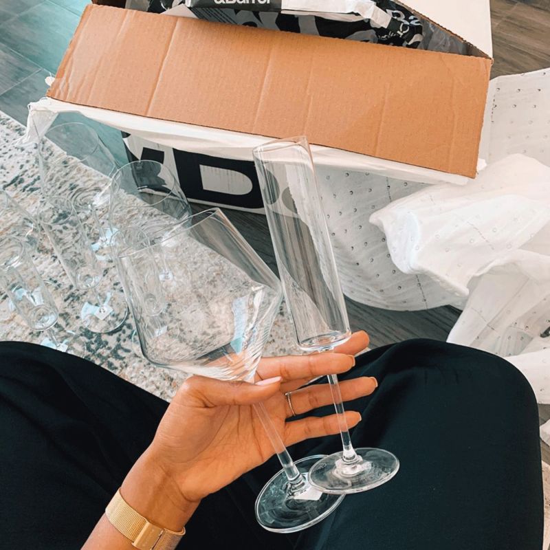 Woman holding two wine glasses with Crate & Barrel box in background