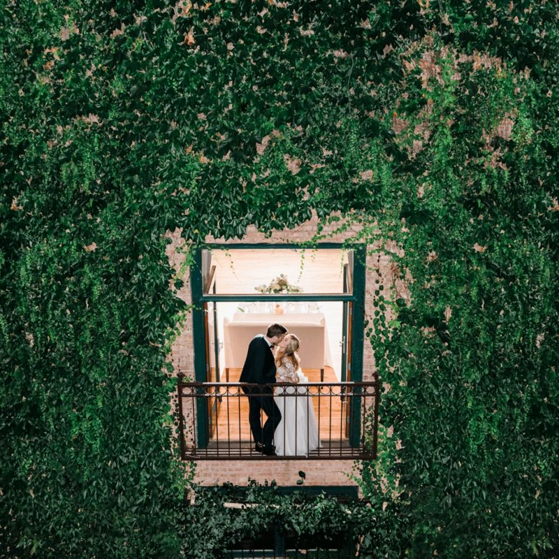 Couple on balcony of a building that is covered in vines