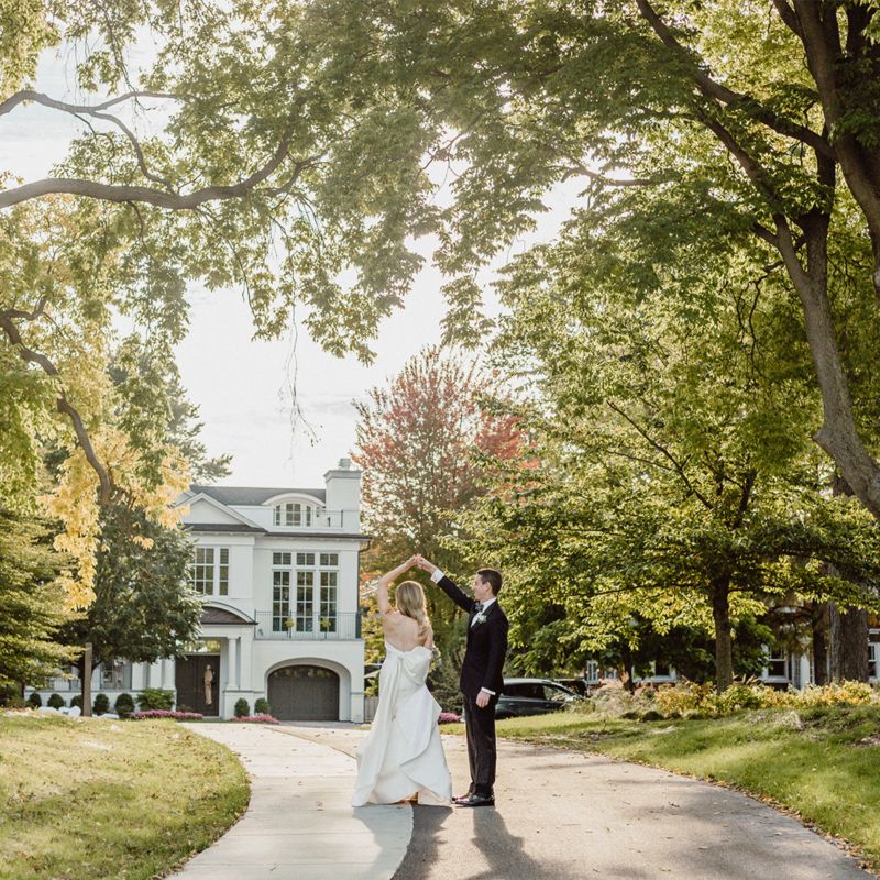 Bride being twirled by husband in home driveway