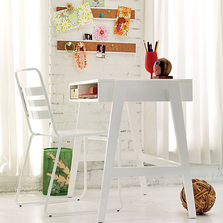 White desk and chair in a painted brick room with tall windows