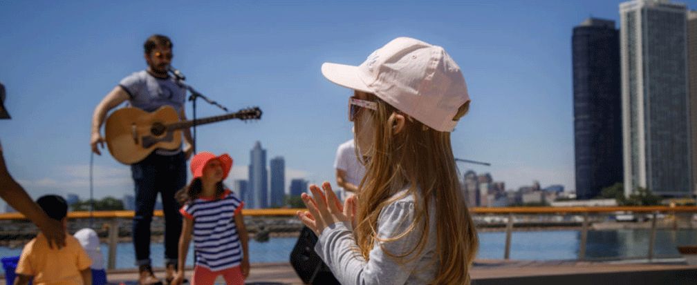 Little girl clapping with guitarist on stage in the background