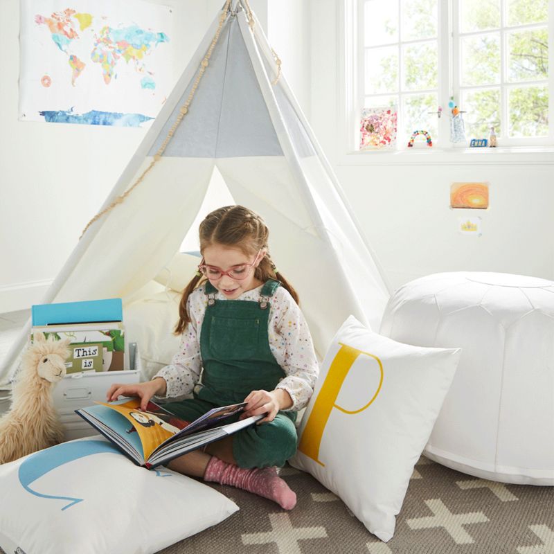 Young girl reading in play teepee