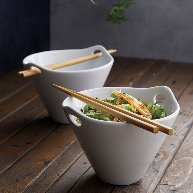 Two noodle bowls with chopsticks filled with soup